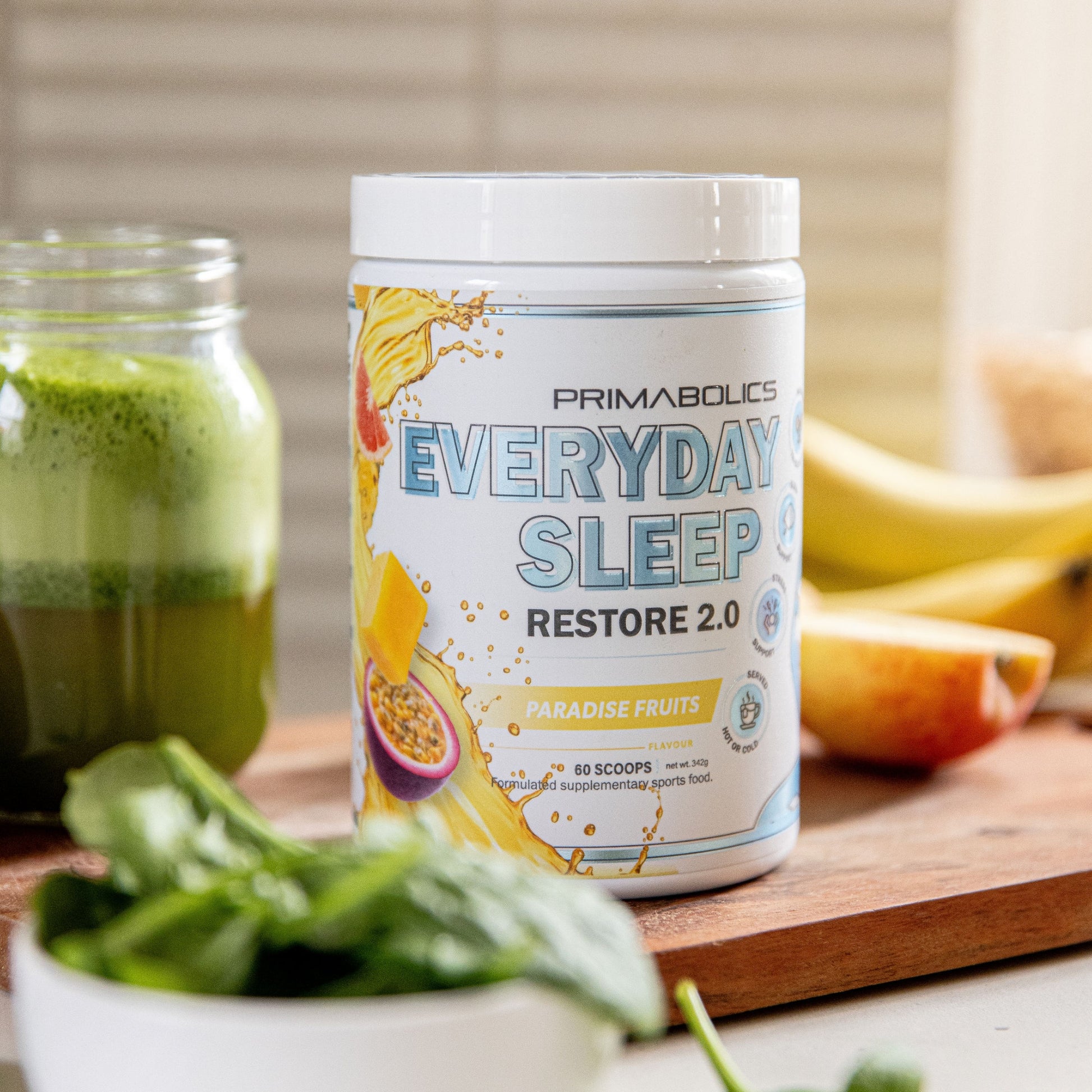 Primabolics Everyday Sleep Restore 2.0 supplement container on a table with a green smoothie and fruits.
