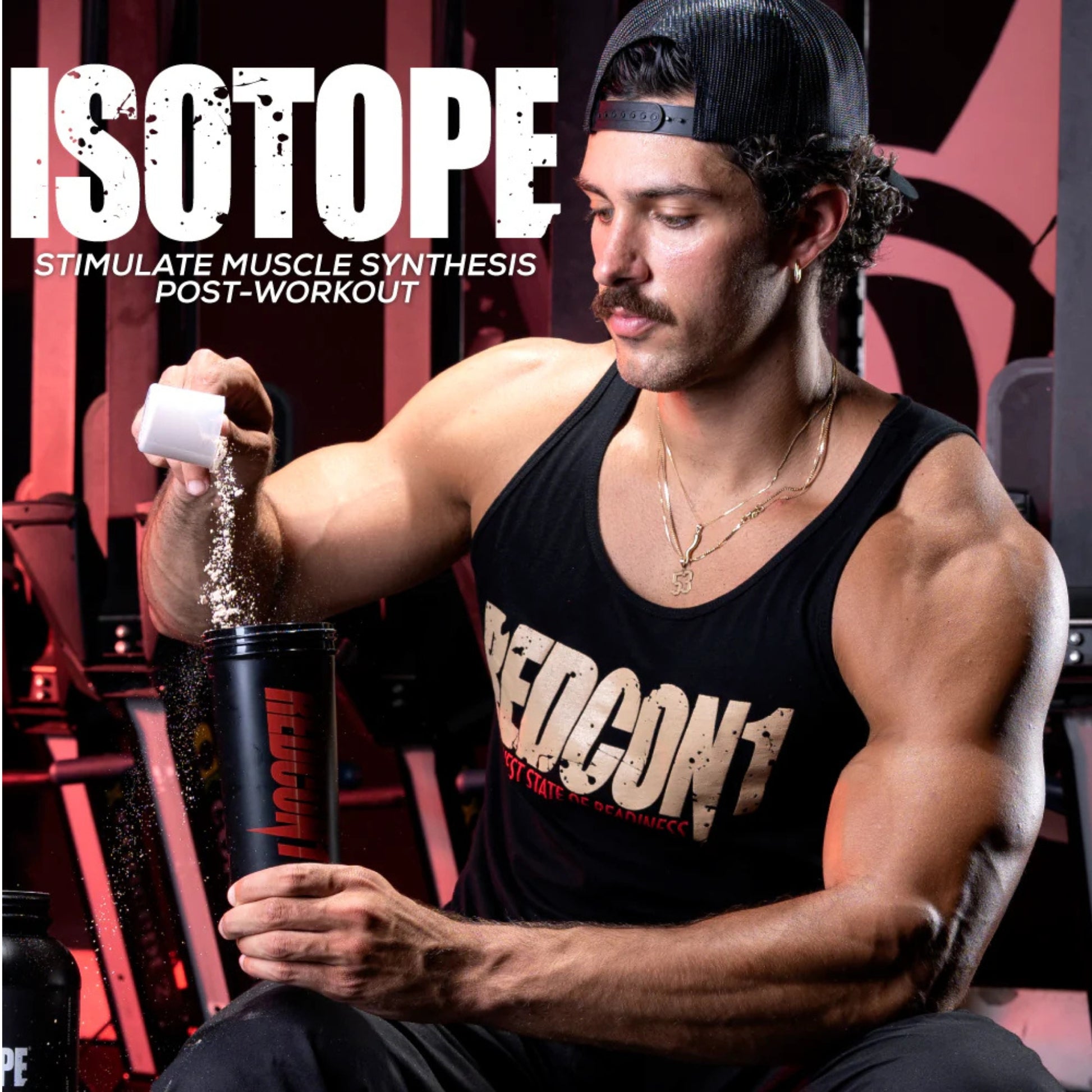 Man in a gym pouring powder into a shaker bottle with 'Isotope' branding.